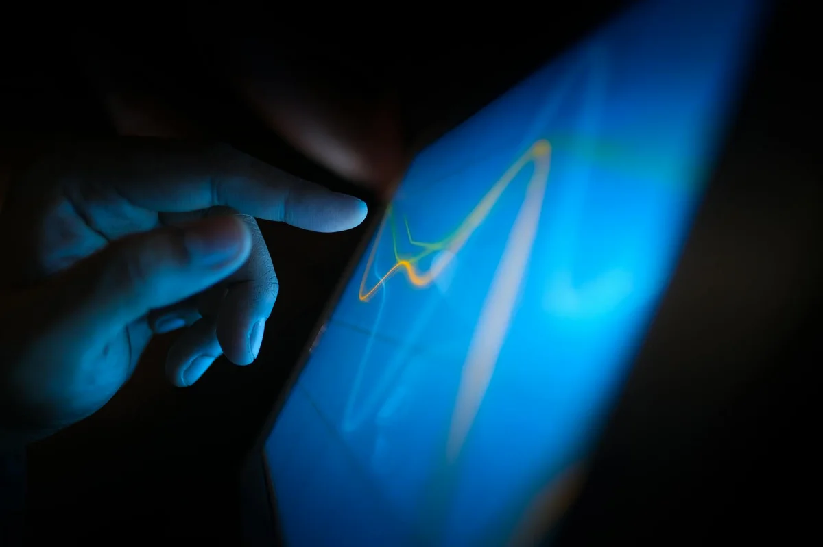 Prompts plantilla reutilizables: tu librería personal de ins... — Close-up of a hand interacting with a touchscreen displaying dynamic graphs.