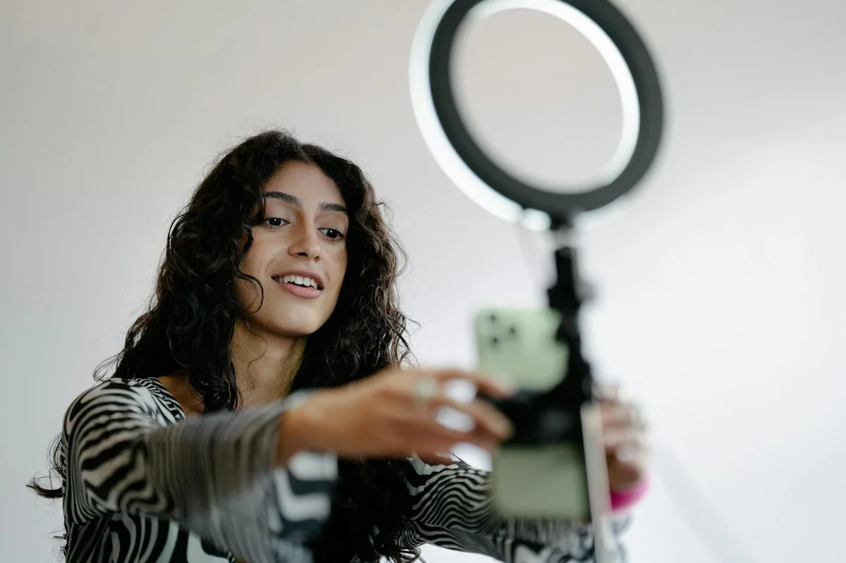 Colaboraciones y marcas en TikTok — Young woman using a smartphone and ring light indoors for recording or streaming