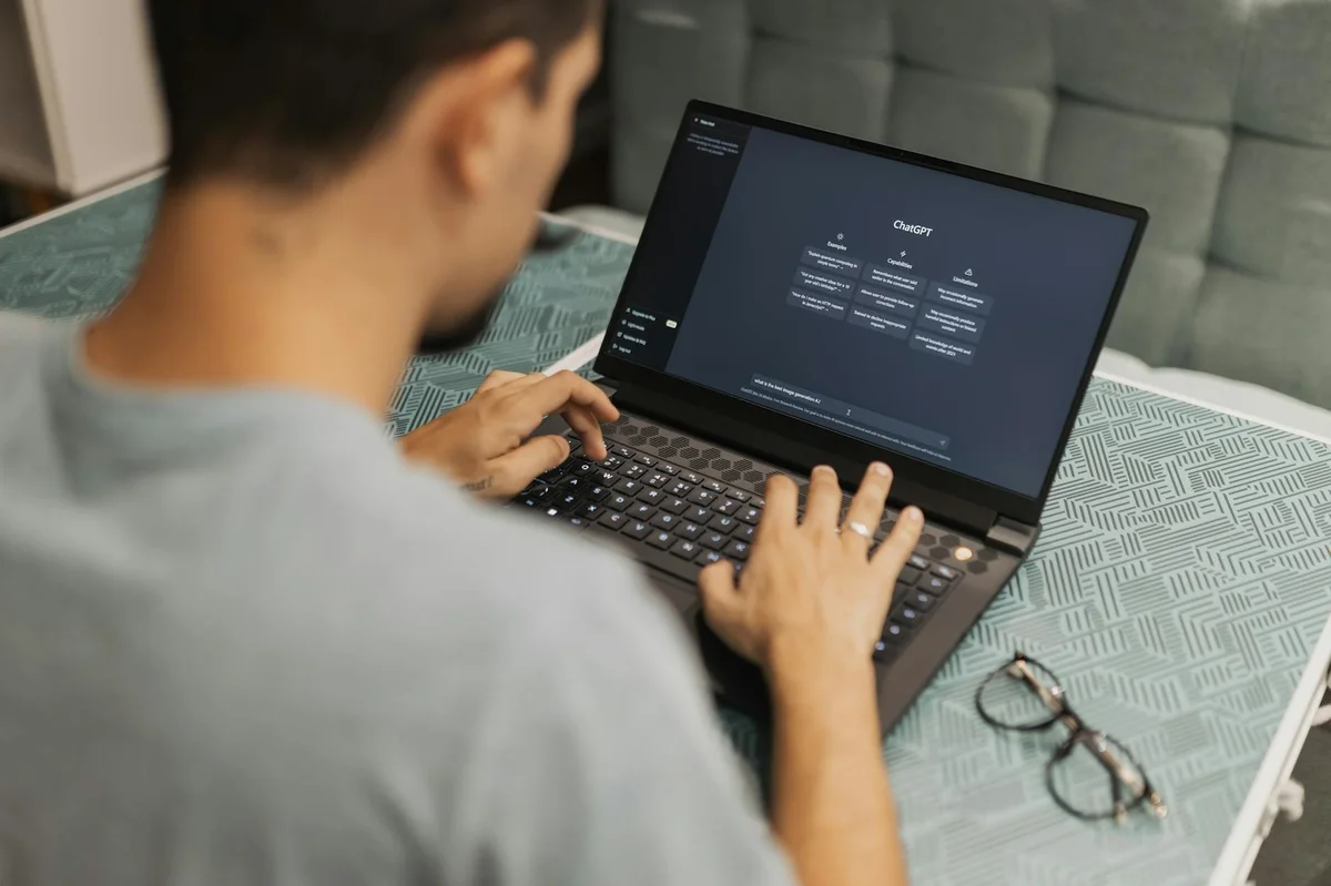 Few-shot IA ejemplos: enseñar el estilo de tu negocio sin de... — Man using laptop with AI interface, typing with focused attention. Indoors with