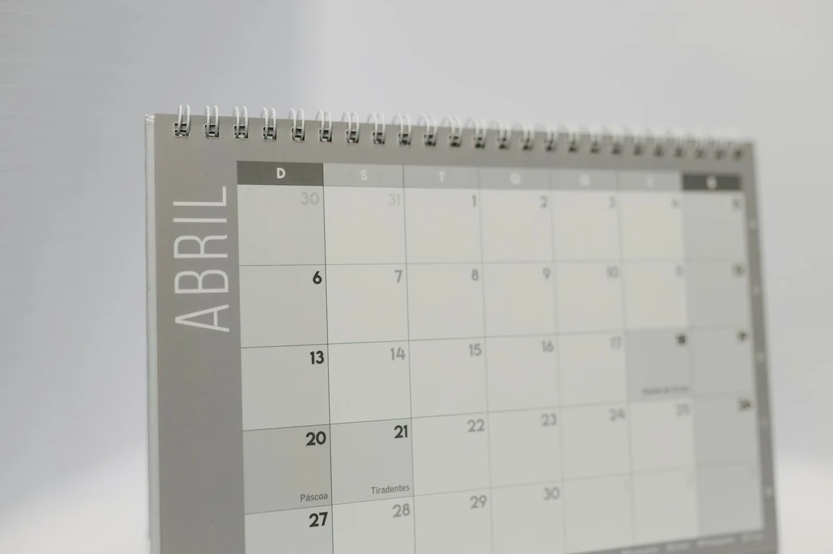 Proyectos largos con IA: cómo gestionar sesiones y pases de... — Close-up of a spiral-bound April desk calendar with a gray minimalistic design.