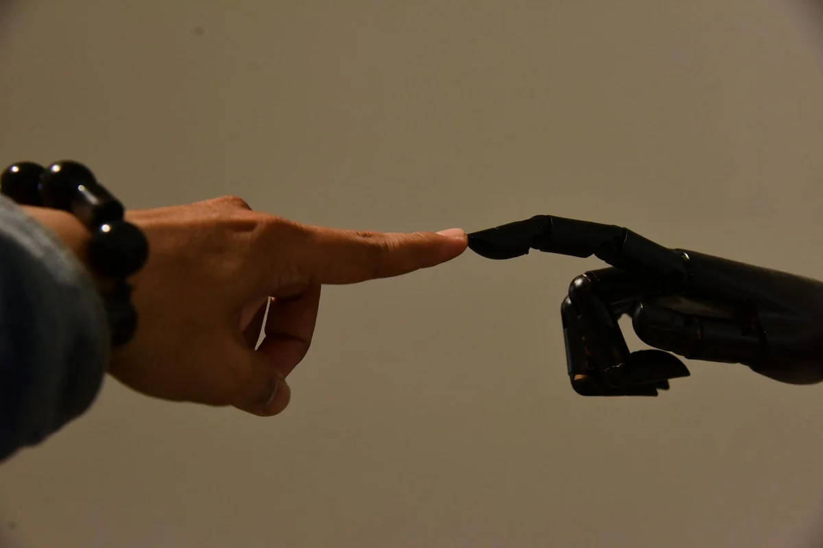 MCP y conectores: cómo enlazar Claude con tus herramientas d... — A human hand and a robotic hand extending fingers to touch, symbolizing connecti