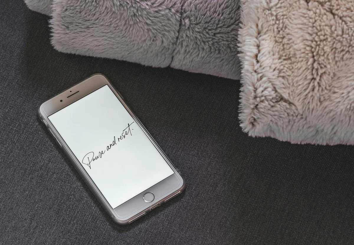 Trabajo Tranquilo: como dejar de correr contra el reloj y re... — A smartphone on a soft surface showing 'Pause and Reset' on the screen.