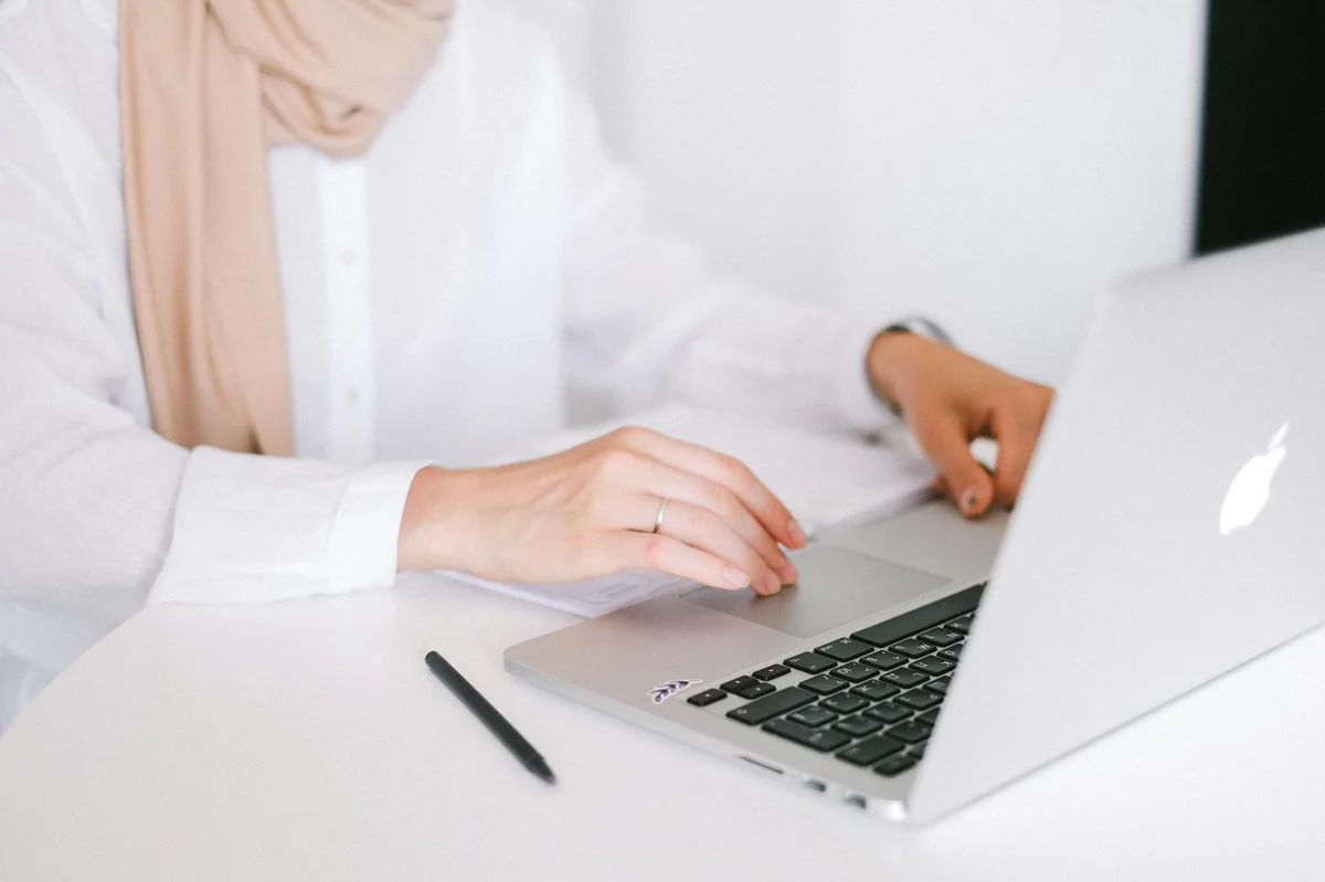 Como escribir guiones sin perder naturalidad — Close-up of a person working on a laptop in a modern home office setting.