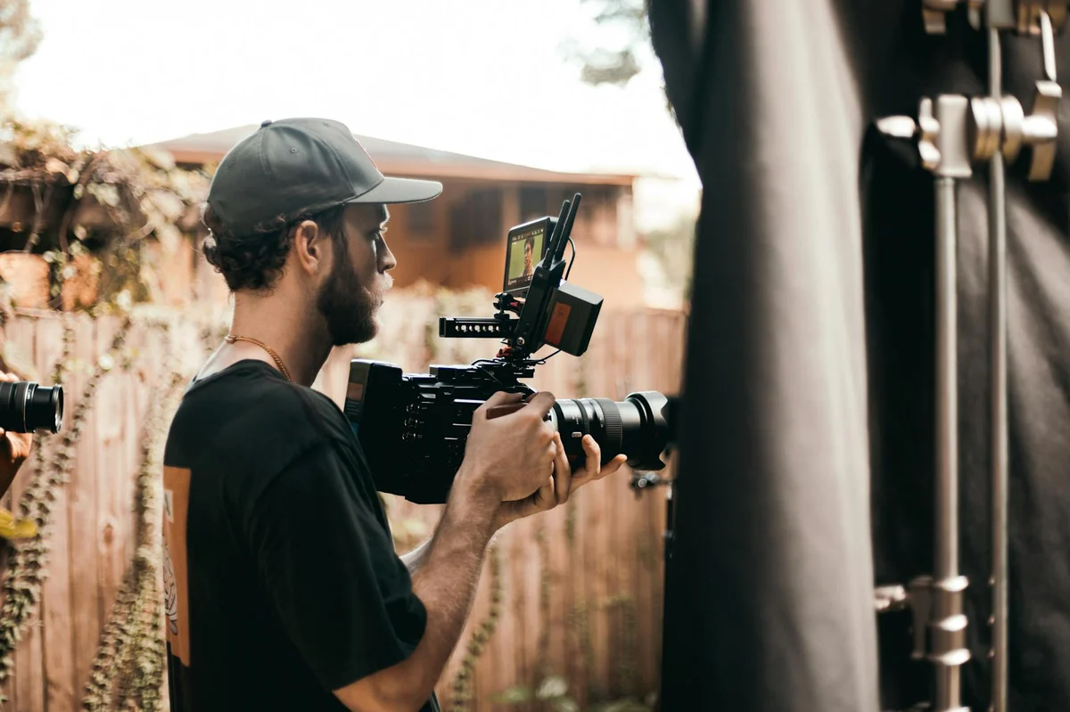 Ritmo de publicación en TikTok: cómo crear contenido sin que... — A side view of a bearded man filming outdoors with professional camera equipment
