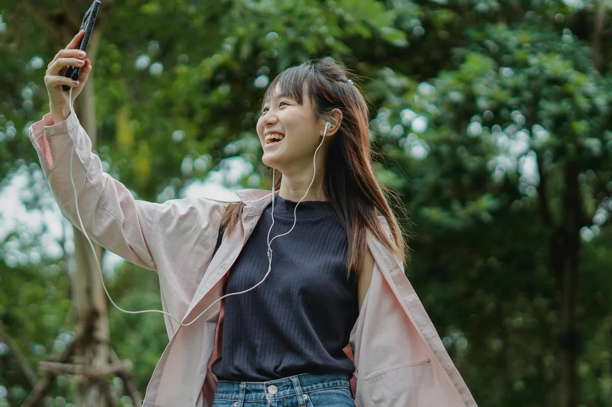 Visibilidad y busqueda en TikTok — Smiling young Asian female in casual clothes talking on phone via video call usi