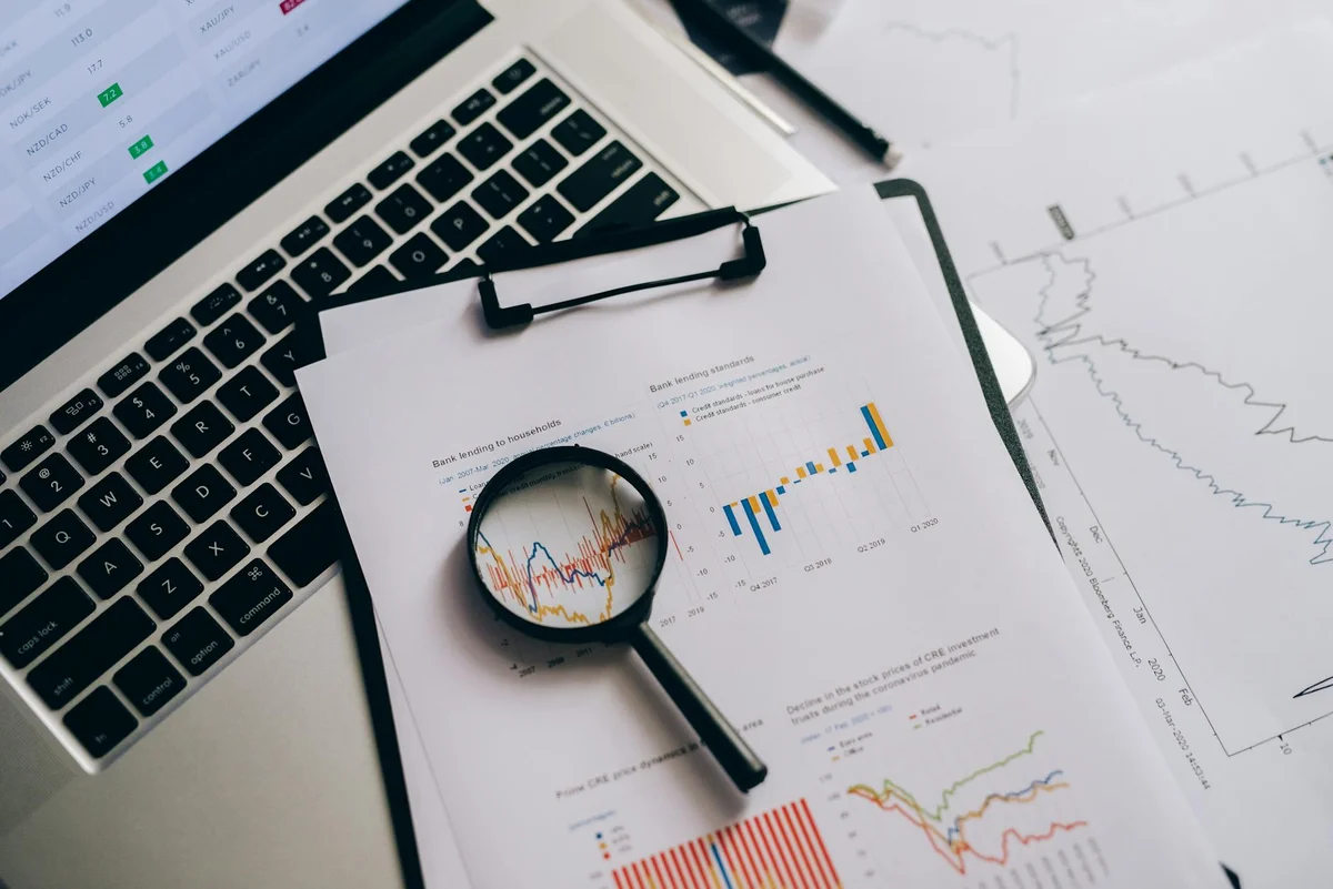 Plugins Claude marketplace: instala capacidades completas co... — Overhead view of financial charts, laptop, and magnifying glass, ideal for busin