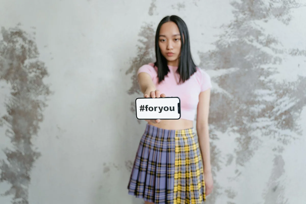 TikTok in 2026: It's Not Just Dancing Anymore — A young woman in a trendy outfit holds a phone displaying #foryou against a text