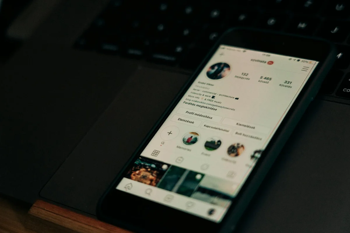 Publicidad en TikTok: guia de TikTok Ads — Close-up of smartphone showing a social media profile screen next to a laptop.