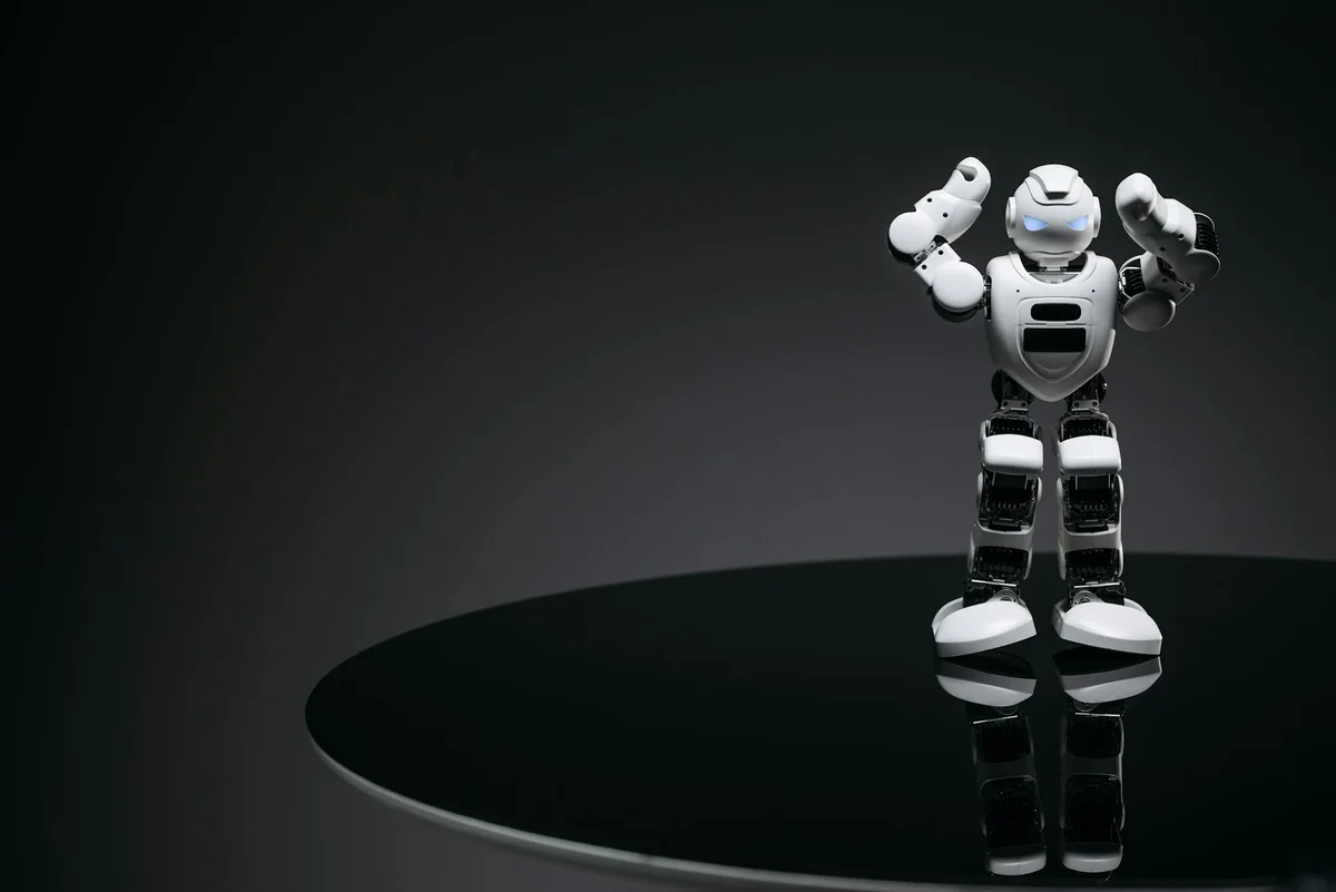 Modelos Claude Opus, Sonnet y Haiku: el mapa de modelos y co... — A small humanoid robot with glowing eyes on a reflective table in a dark setting