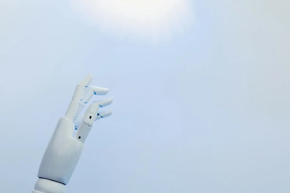 Auditar decisiones con IA: usar Claude contra ti mismo — A robotic hand reaching towards a bright light on a white background symbolizing