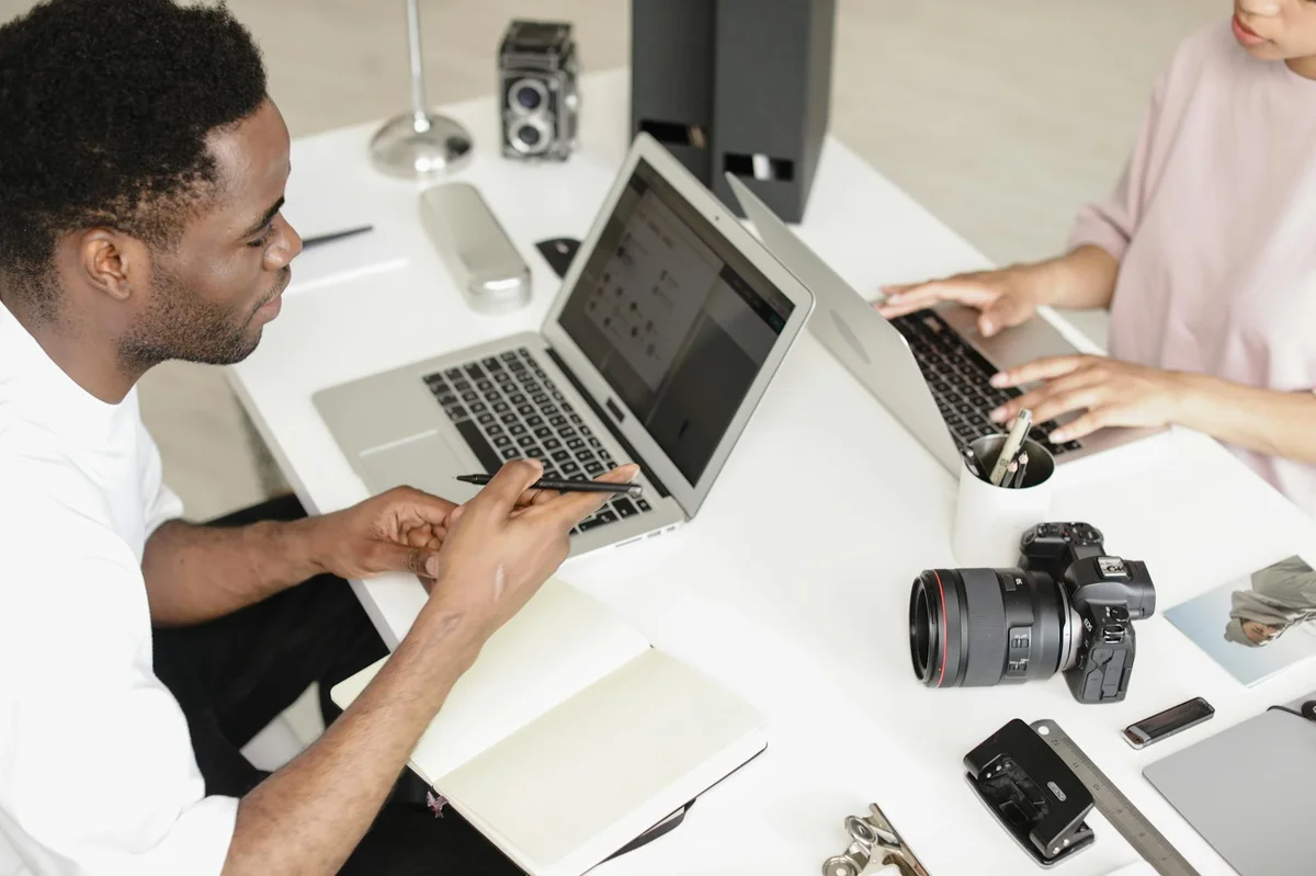 TikTok como herramienta de negocio — Photographers collaborating in a modern workspace with cameras and laptops.