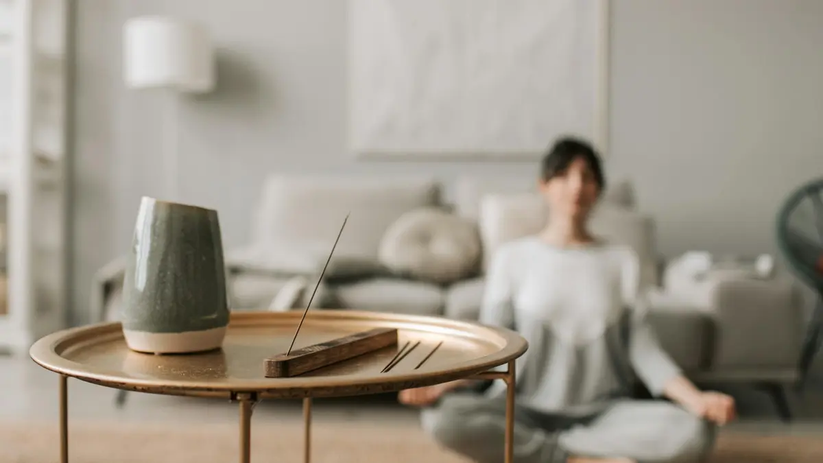 Calm living room scene with incense and a woman meditating, perfect for relaxation concepts.