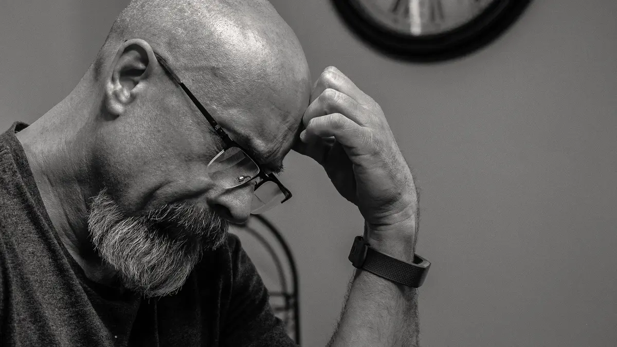 Black and white portrait of a thoughtful bald man indoors, capturing a moment of reflection with a w
