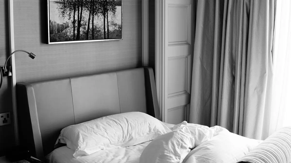 A stylish bedroom with monochrome decor, featuring a bed and artistic wall art.